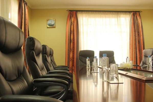 A conference room with leather chairs, a long table with water bottles, and a view through large windows with curtains. - LIA Hotel & Training Centre (Nairobi)