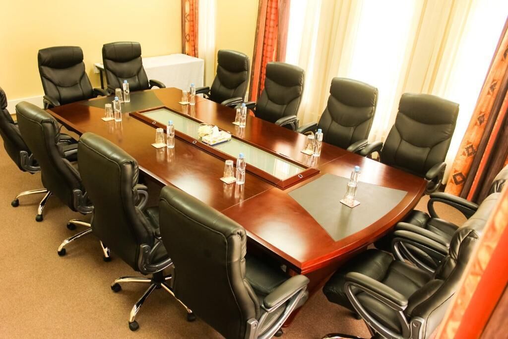A conference room with a large rectangular table, black leather chairs, and water bottles on the table.