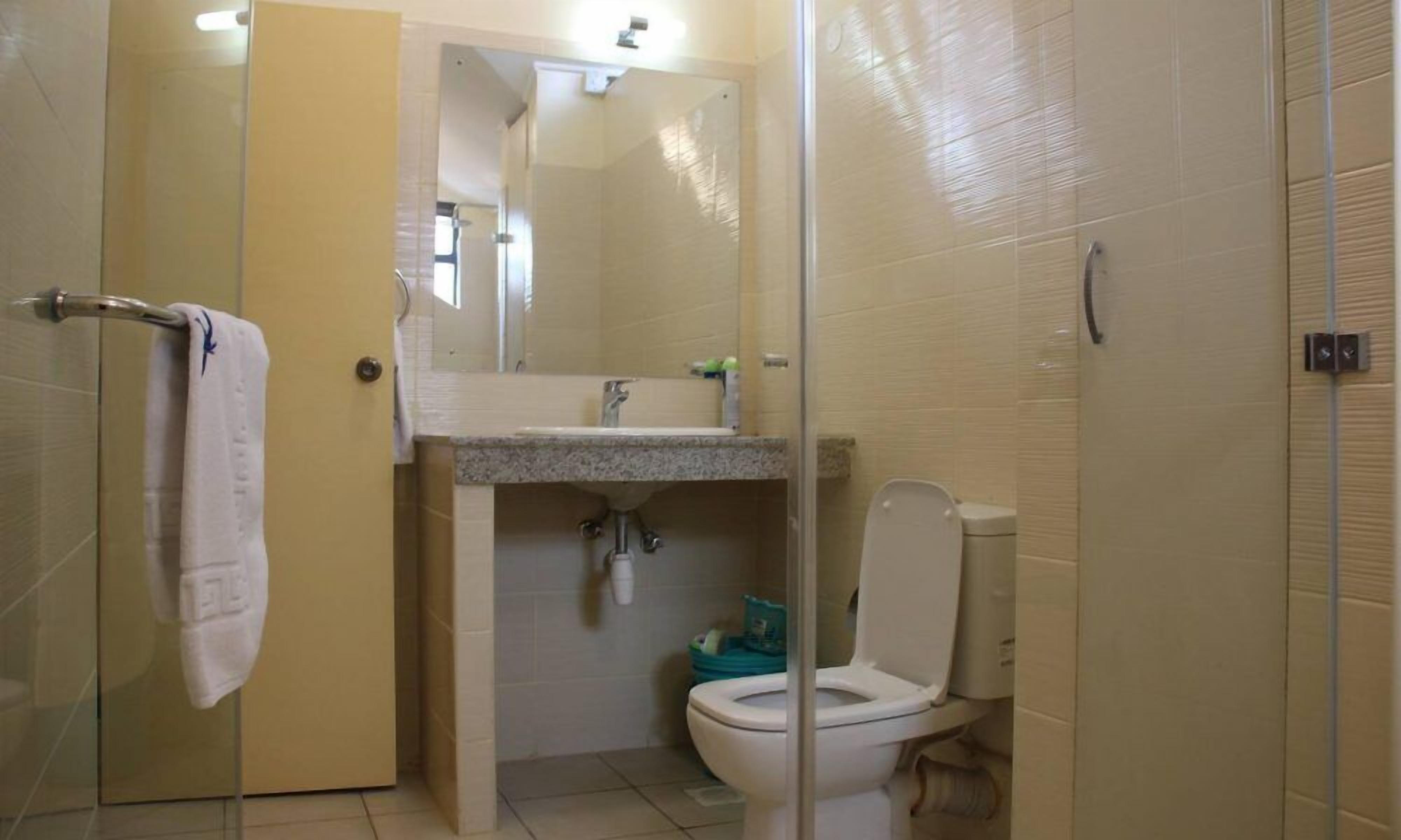 A bathroom with a toilet, sink, and glass shower enclosure.