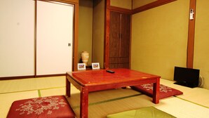 A traditional Japanese room with tatami flooring, a wooden table, and a red cushion. - Guesthouse Tomoshibi - Hostel (Matsumoto)