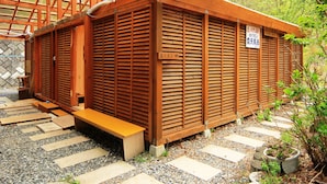 A traditional Japanese building with a wooden exterior, a covered entrance, and a stone pathway leading to a bench. - Guesthouse Tomoshibi - Hostel (Matsumoto)