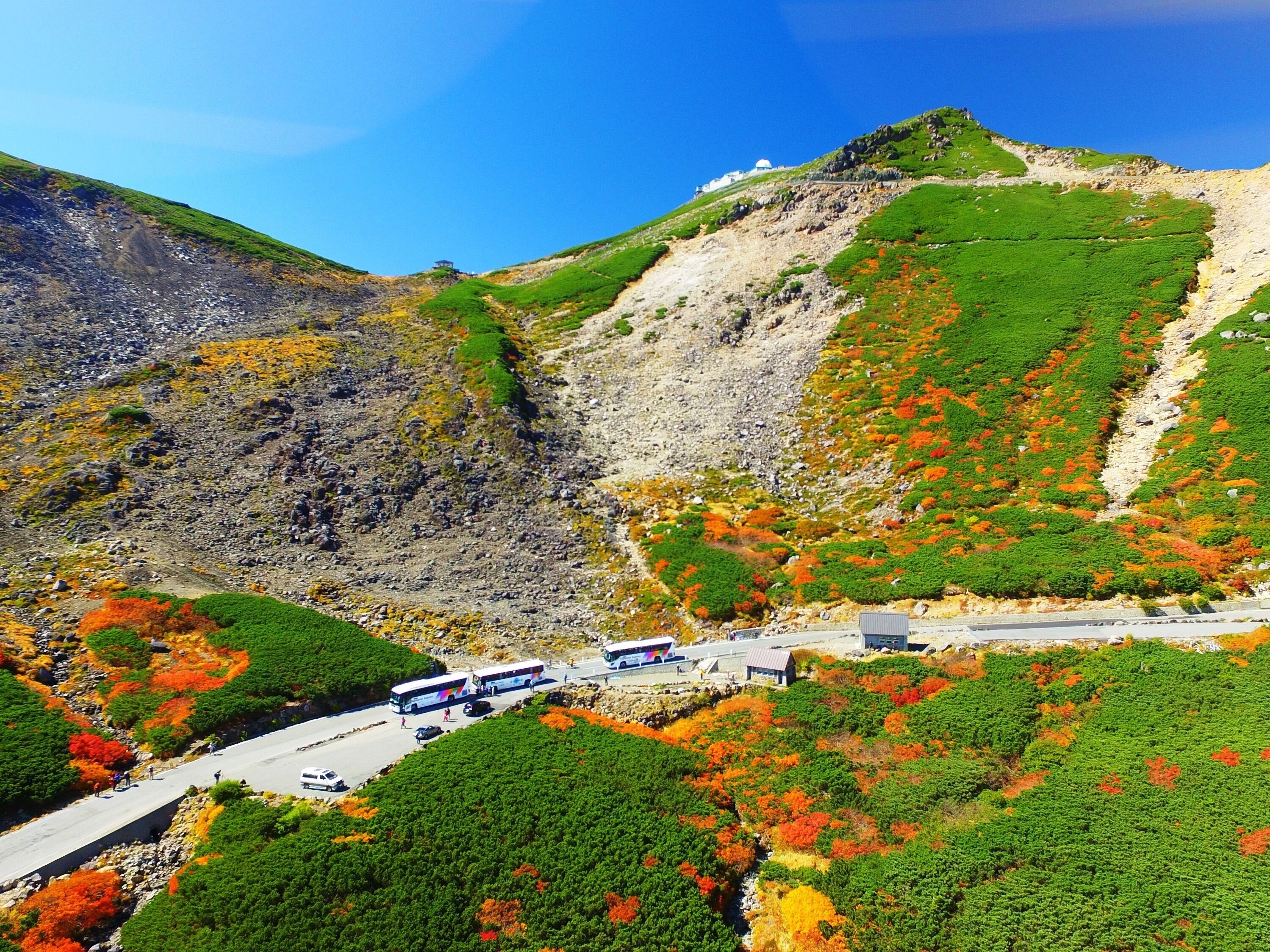A mountainous landscape with a road, a bus, and a building.