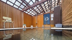 A clean indoor swimming pool with wooden walls and a glass floor, equipped with a changing area and towels. - Guesthouse Tomoshibi - Hostel (Matsumoto)