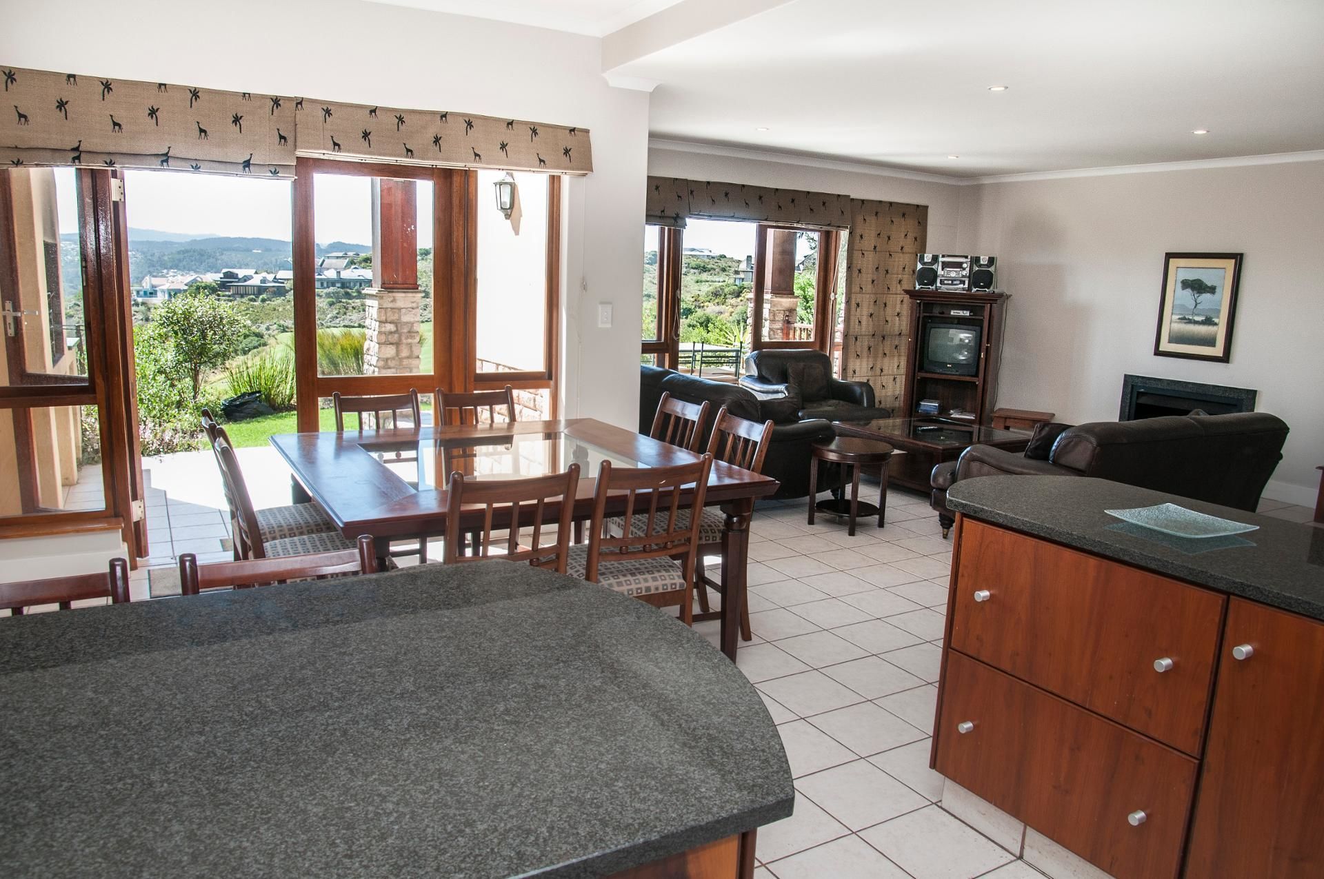 A spacious living area with a dining table, a sofa, and a kitchen area with a TV and cabinets.