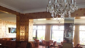 A spacious hotel lobby with a chandelier, a television, and a fireplace.