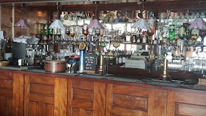 A bar area with a variety of liquor bottles, a cash register, and a coffee machine.