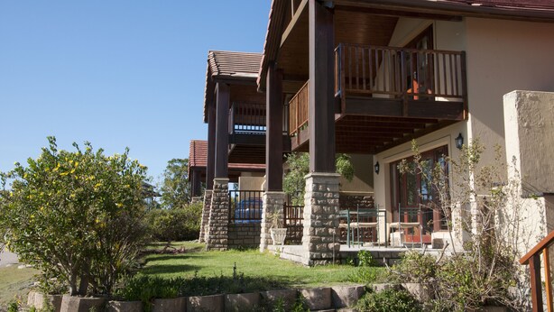 A two-story building with a balcony, stone pillars, and a well-maintained lawn. - Villa 9 (Knysna)