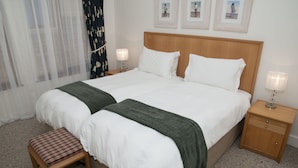 A double bed with white linens, a wooden headboard, and a nightstand with a lamp. - Villa 9 (Knysna)