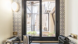 A kitchen with a toaster, kettle, and electric kettle on the counter, a window with a view of the street, and patterned tiles on the walls. - Monti Stairway to Heaven (Rome)