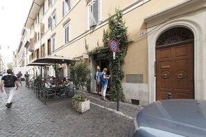 A cobblestone street with outdoor seating, a closed shop, and a brown door.