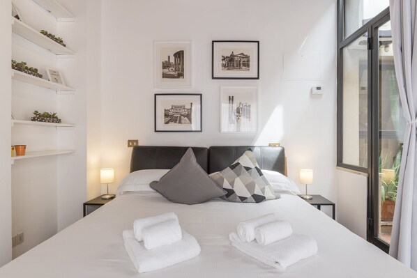 A hotel room with a large bed, two bedside tables, a headboard, and four framed pictures on the wall.