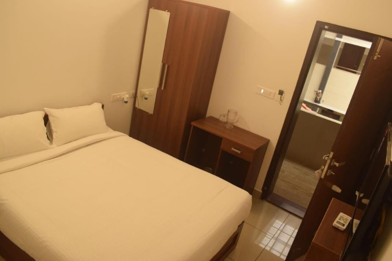 Una habitación de hotel con una cama, un armario de madera, un escritorio y un espejo.