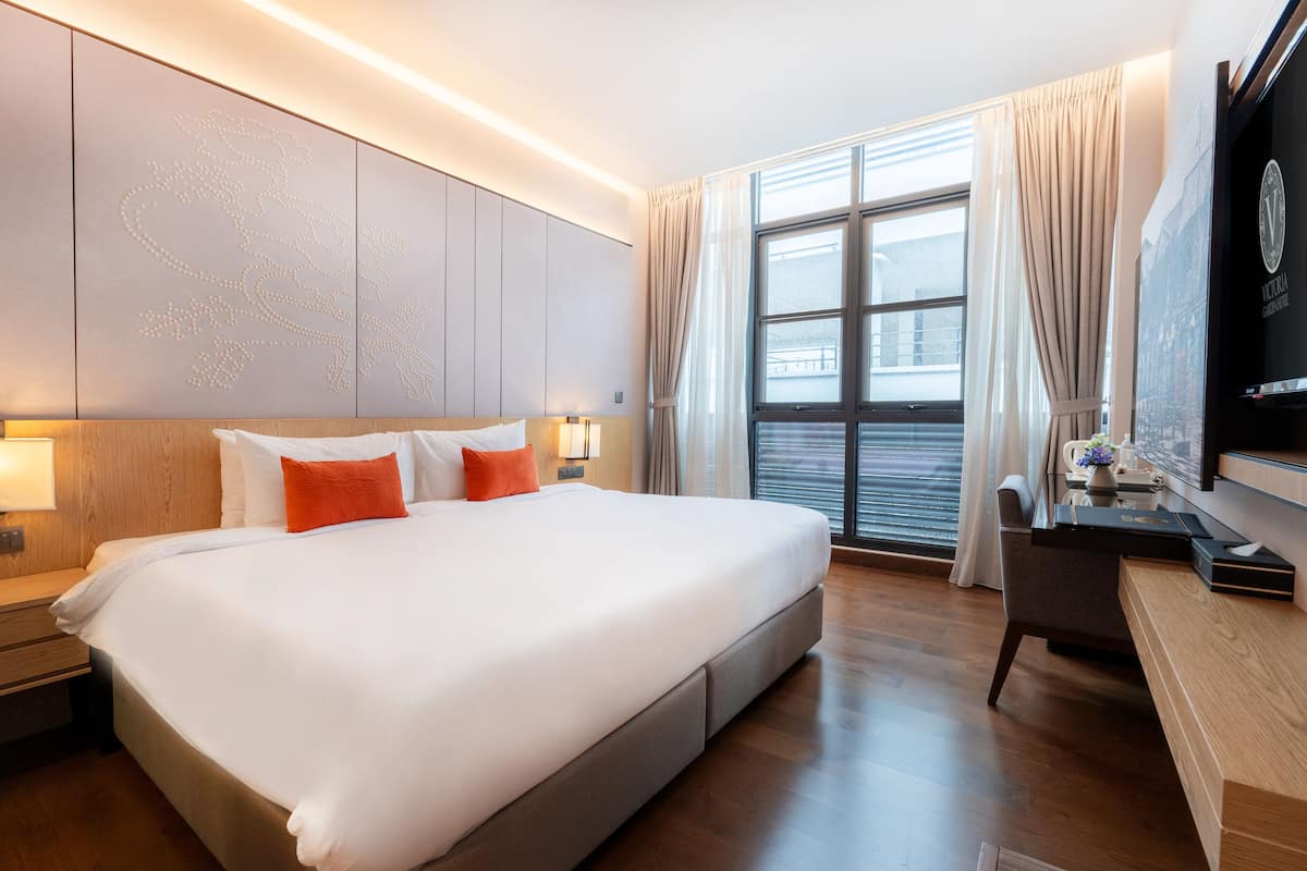 A modern hotel room with a large bed, a desk, and a television.