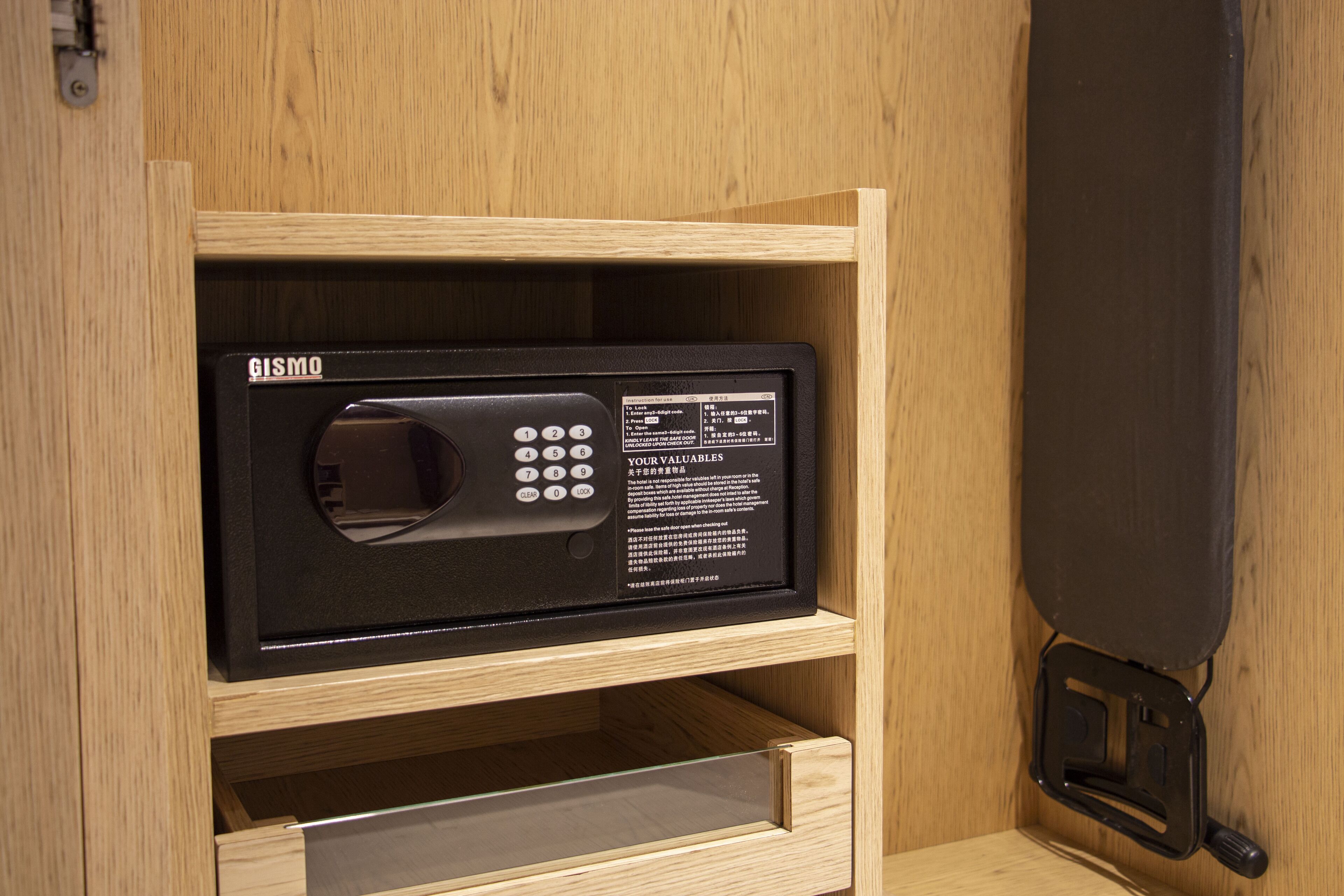 A black microwave with a digital display and instructions, placed in a wooden drawer unit within a wooden cabinet.