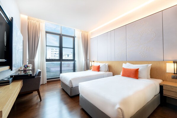 A hotel room with two beds, a desk, a chair, and a large window with curtains. - Victoria Garden Hotel (George Town)