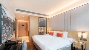 A modern hotel room with a large bed, bedside tables, a desk, and a seating area. - Victoria Garden Hotel (George Town)