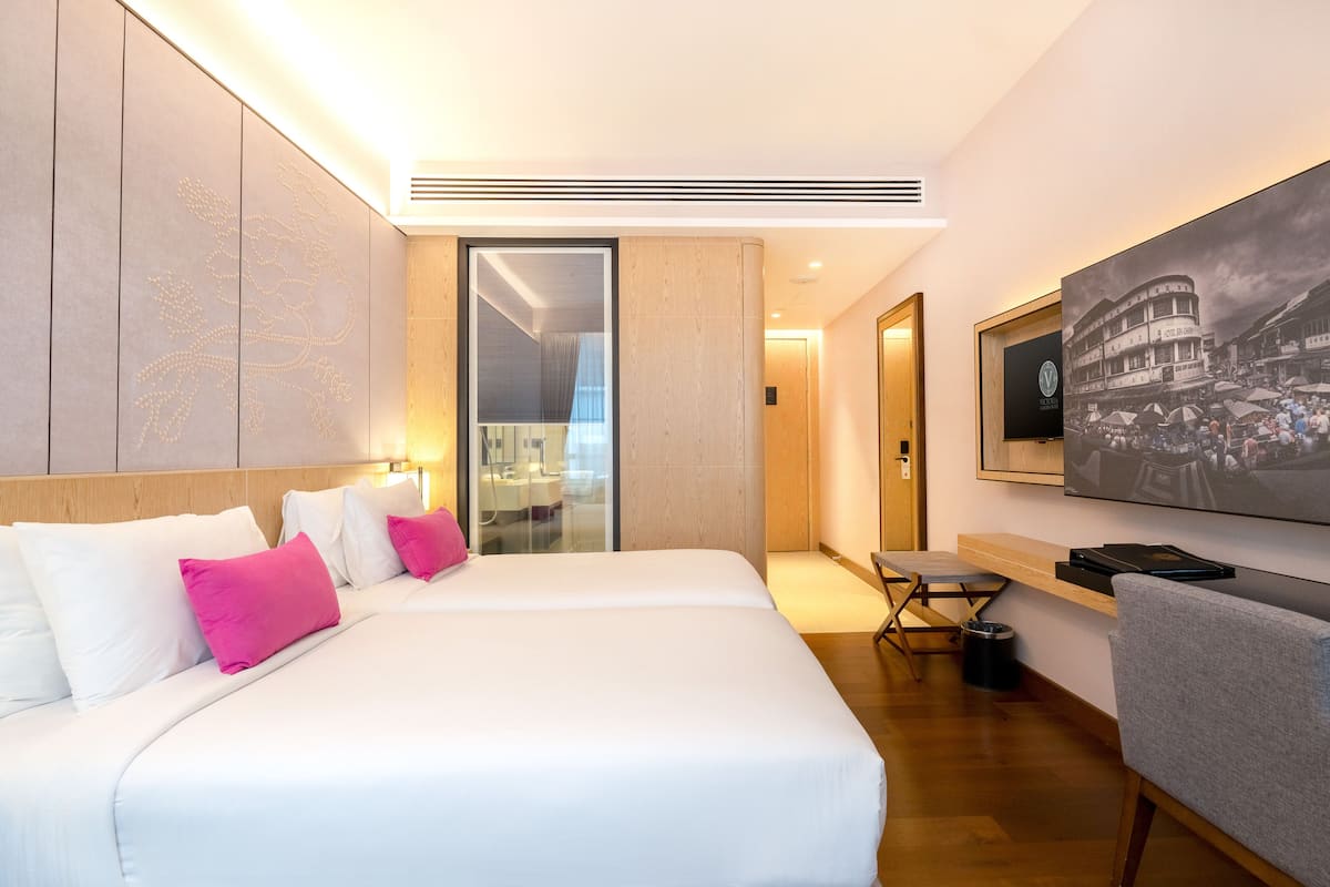 A modern hotel room with a large bed, a desk, and a TV mounted on the wall.