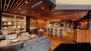 A modern restaurant with wooden ceiling beams, bar area, and seating arrangements. - Victoria Garden Hotel (George Town)