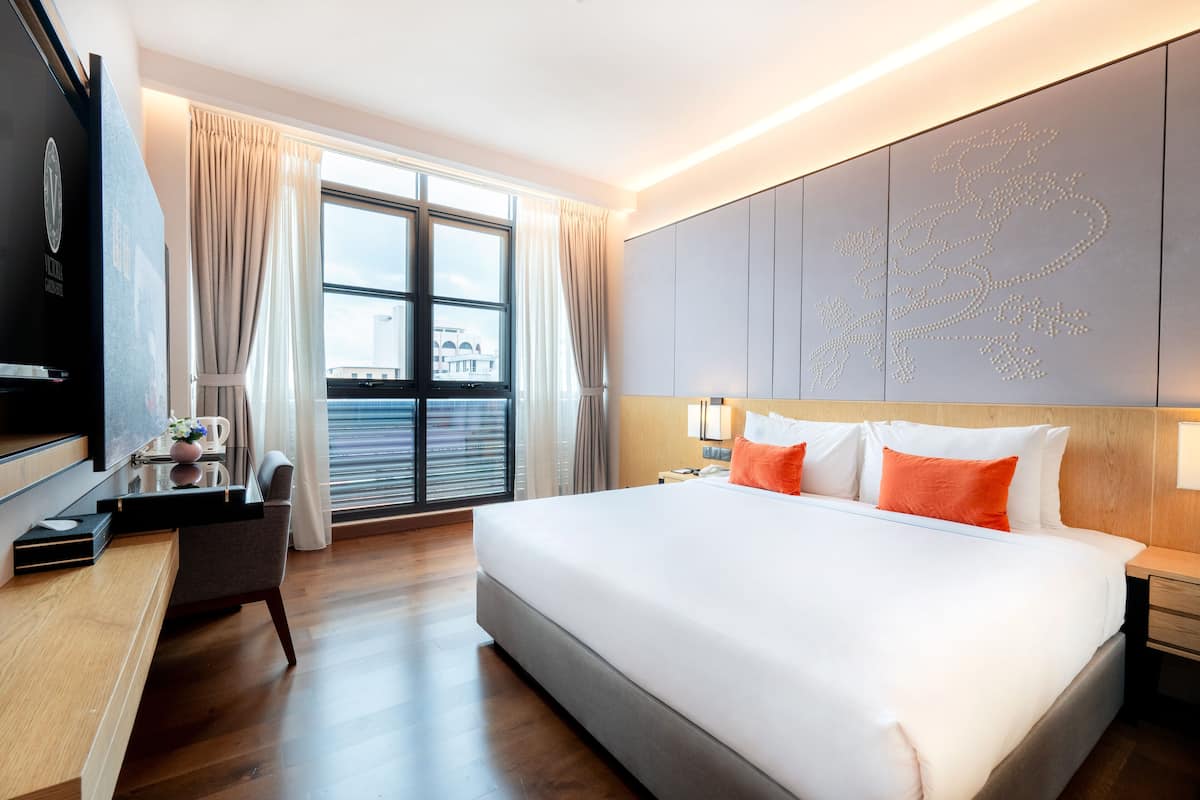 A modern hotel room with a large bed, a desk, and a TV.