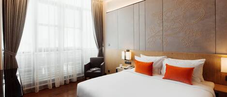Habitación de hotel con una cama grande, una mesita de noche, una silla y un panel decorativo en la pared.