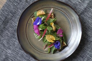 A plate with a salad on a textured tablecloth.