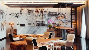 A modern hotel lobby with a large abstract mural, comfortable seating, and a polished floor. - Victoria Garden Hotel (George Town)