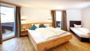 Een hotelkamer met een groot bed, een kleiner bed, een bureau en een stoel.