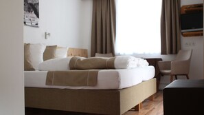 Una habitación de hotel con una cama, un escritorio y una silla.