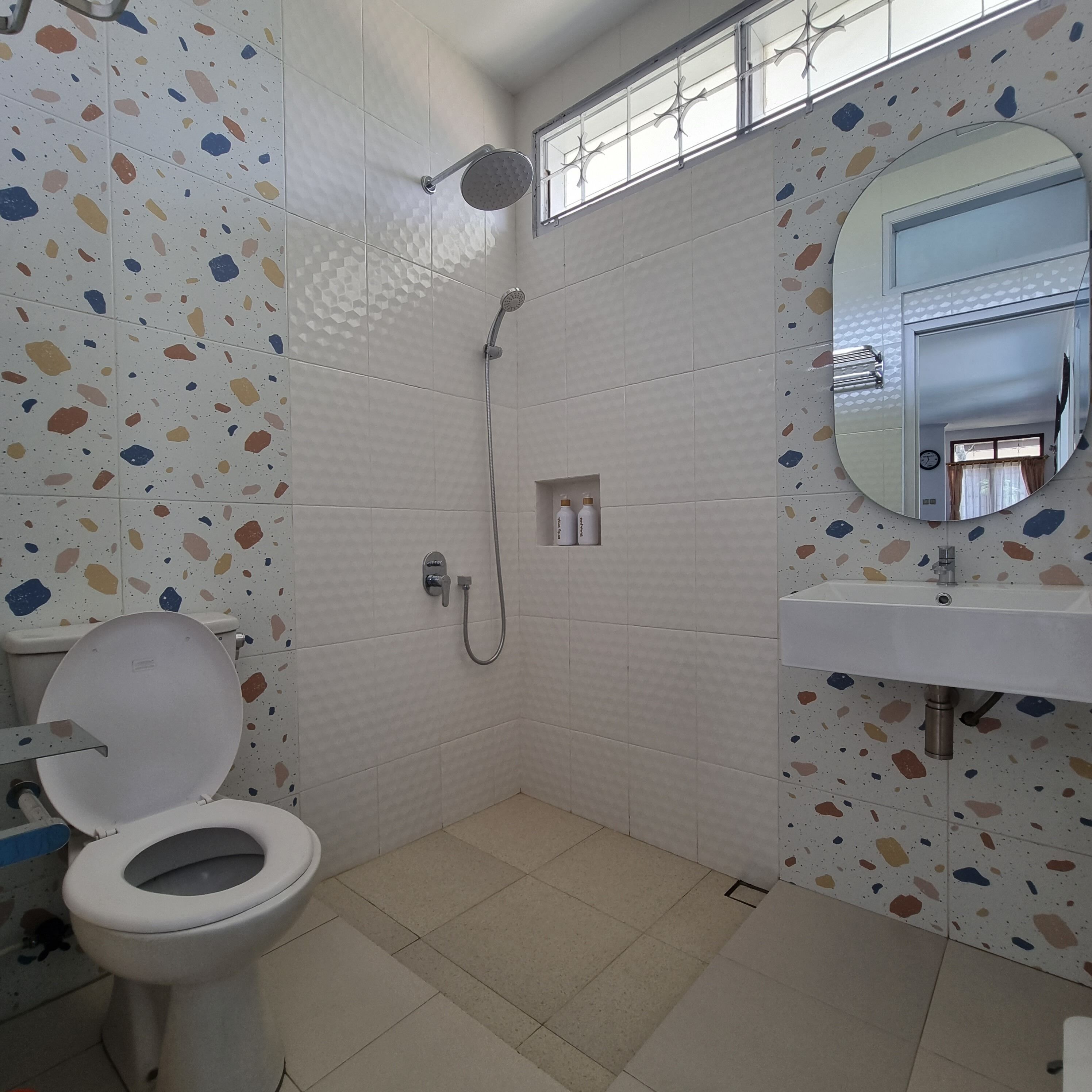 A bathroom with a toilet, shower, and sink.