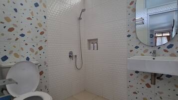A bathroom with a toilet, shower, and sink.