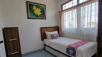 A bedroom with a bed, a wardrobe, a window with curtains, and a painting on the wall.
