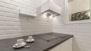 Een keuken met witte metrotegels, een zwart aanrechtblad en een raam met uitzicht op bomen.