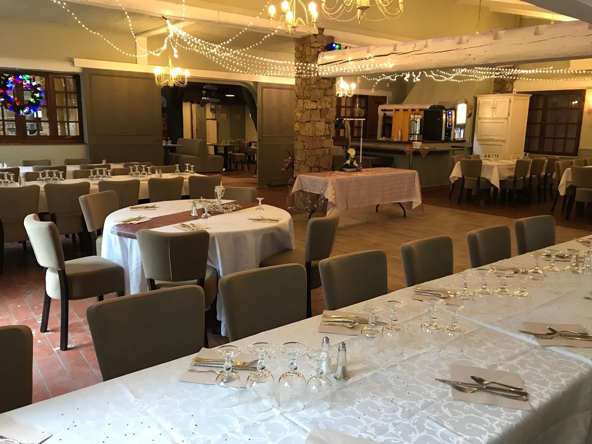 A banquet hall with round tables set for dining, featuring white tablecloths and glassware.