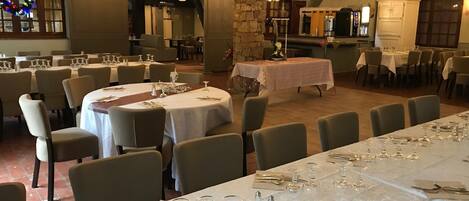 A banquet hall with round tables set for dining, featuring white tablecloths and glassware.