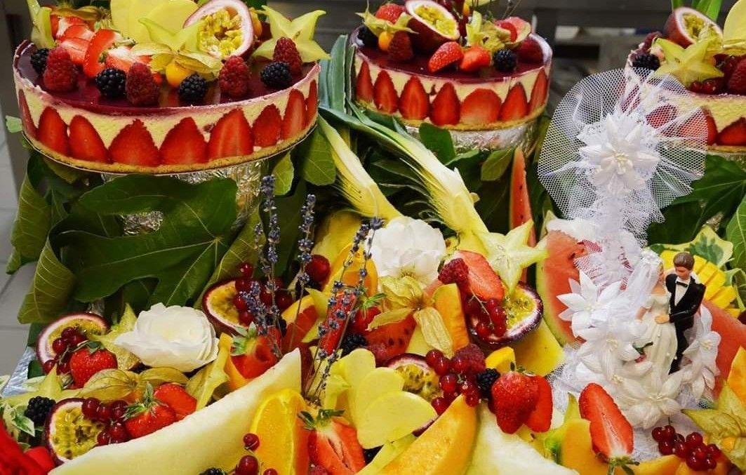 Una composición de frutas con un pastel de bodas y un adorno decorativo.