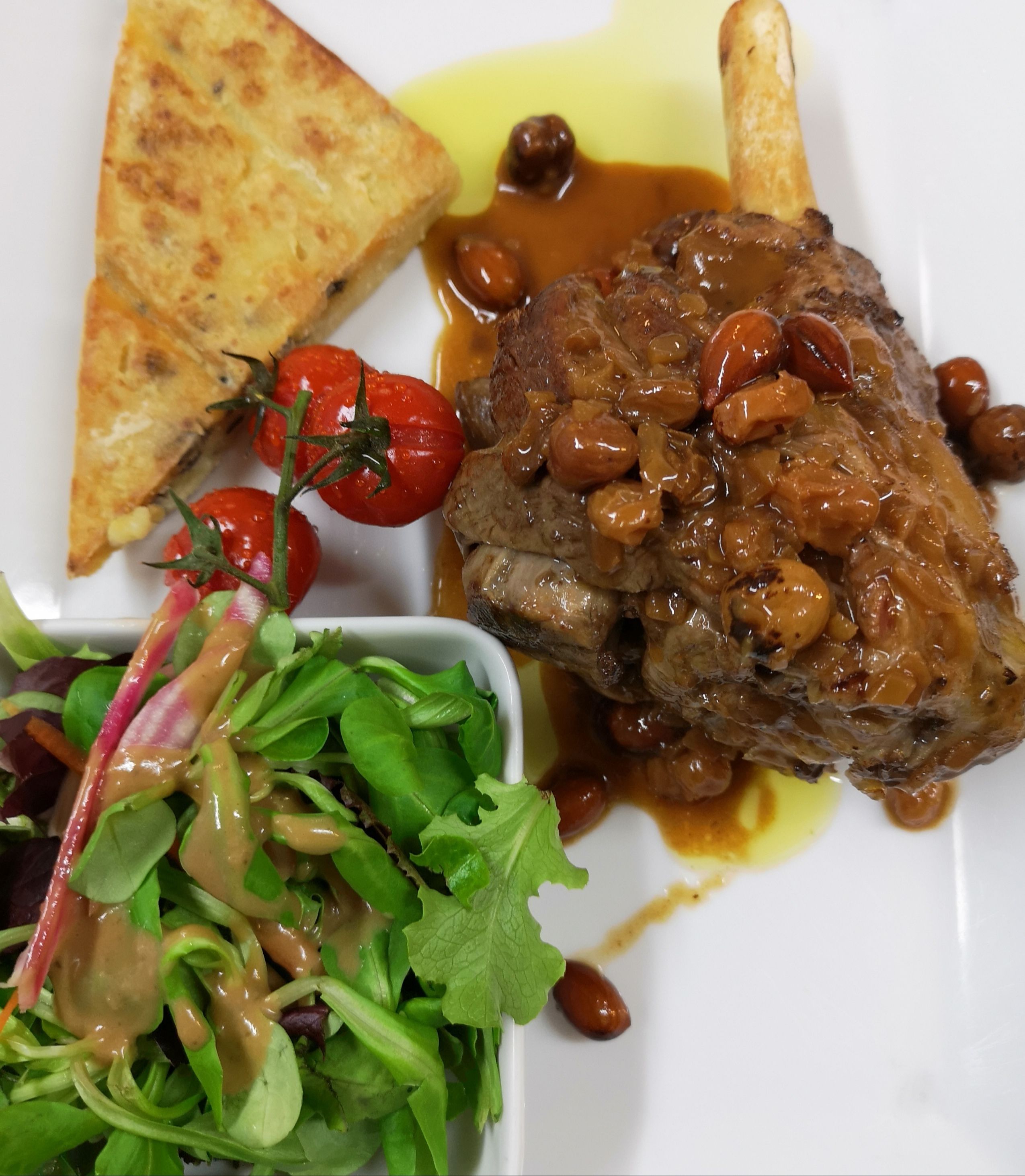 Een bord met een gegrilde steak, belegd met bonen, een geroosterde boterham, kerstomaatjes en een salade.