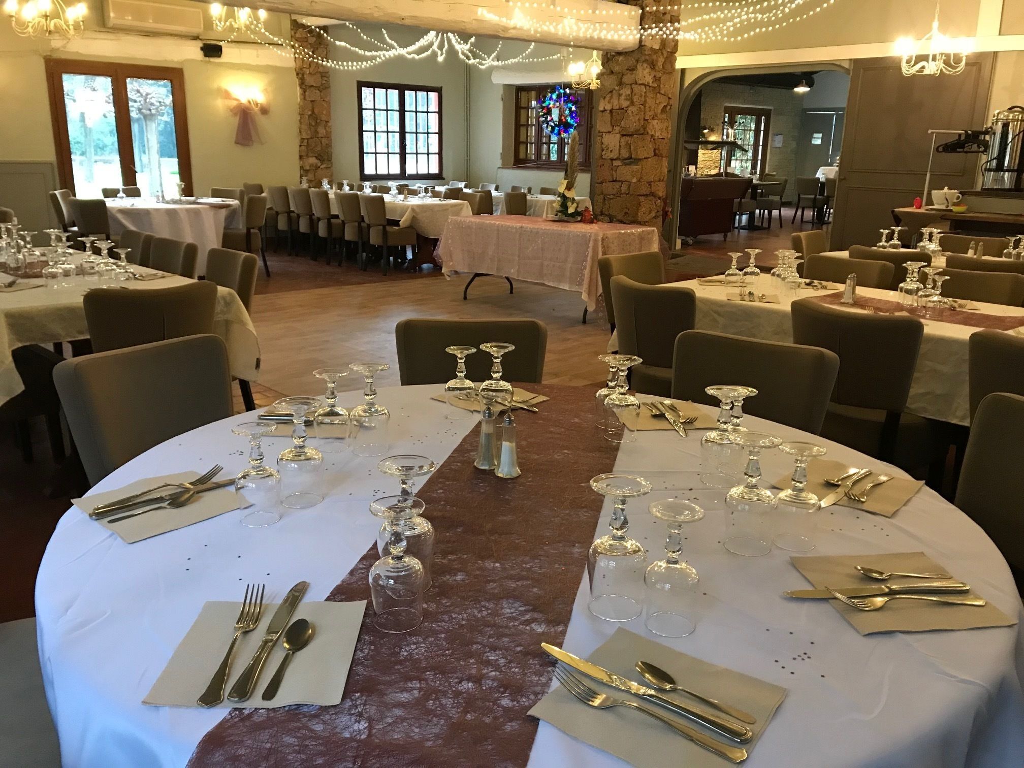 Un salón de banquetes con mesas redondas dispuestas para cenar, con manteles blancos, cubiertos y copas de vino.