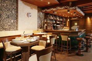 Un restaurante con muebles de madera, una zona de bar y una pared de piedra.