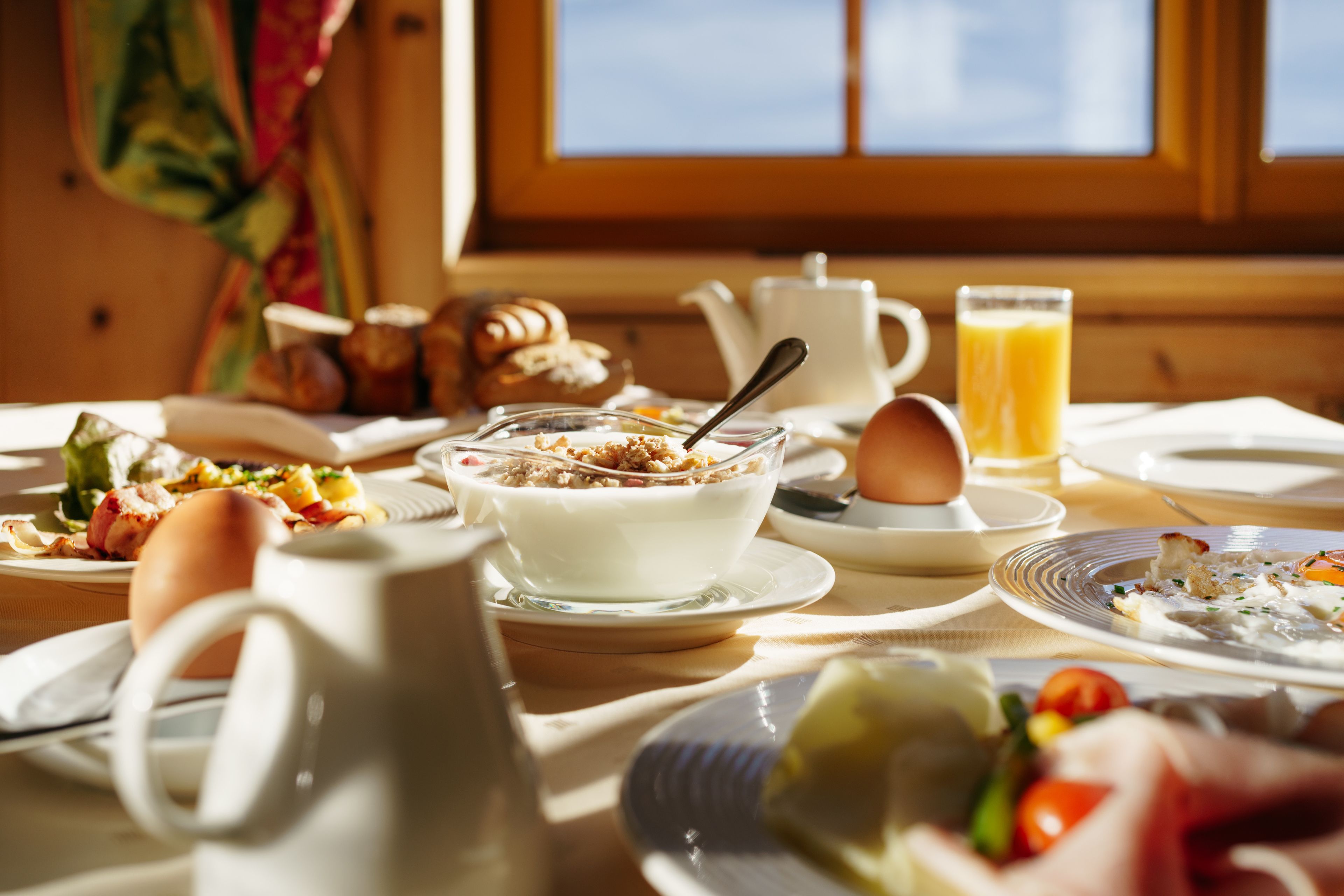 Ein Frühstückstisch mit verschiedenen Speisen, darunter Eier, Toast und ein Glas Orangensaft.