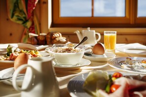 Una mesa de desayuno con diferentes platos, como huevos, tostadas y un vaso de jugo de naranja.