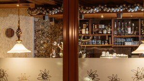 A bar area with shelves of liquor bottles and glasses, a decorative ceiling, and a patterned wall. - Hotel Venter Bergwelt (Soelden)