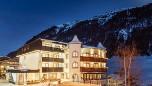 A multi-story hotel with a snow-covered mountain backdrop, featuring balconies and a lit facade. - Hotel Venter Bergwelt (Soelden)