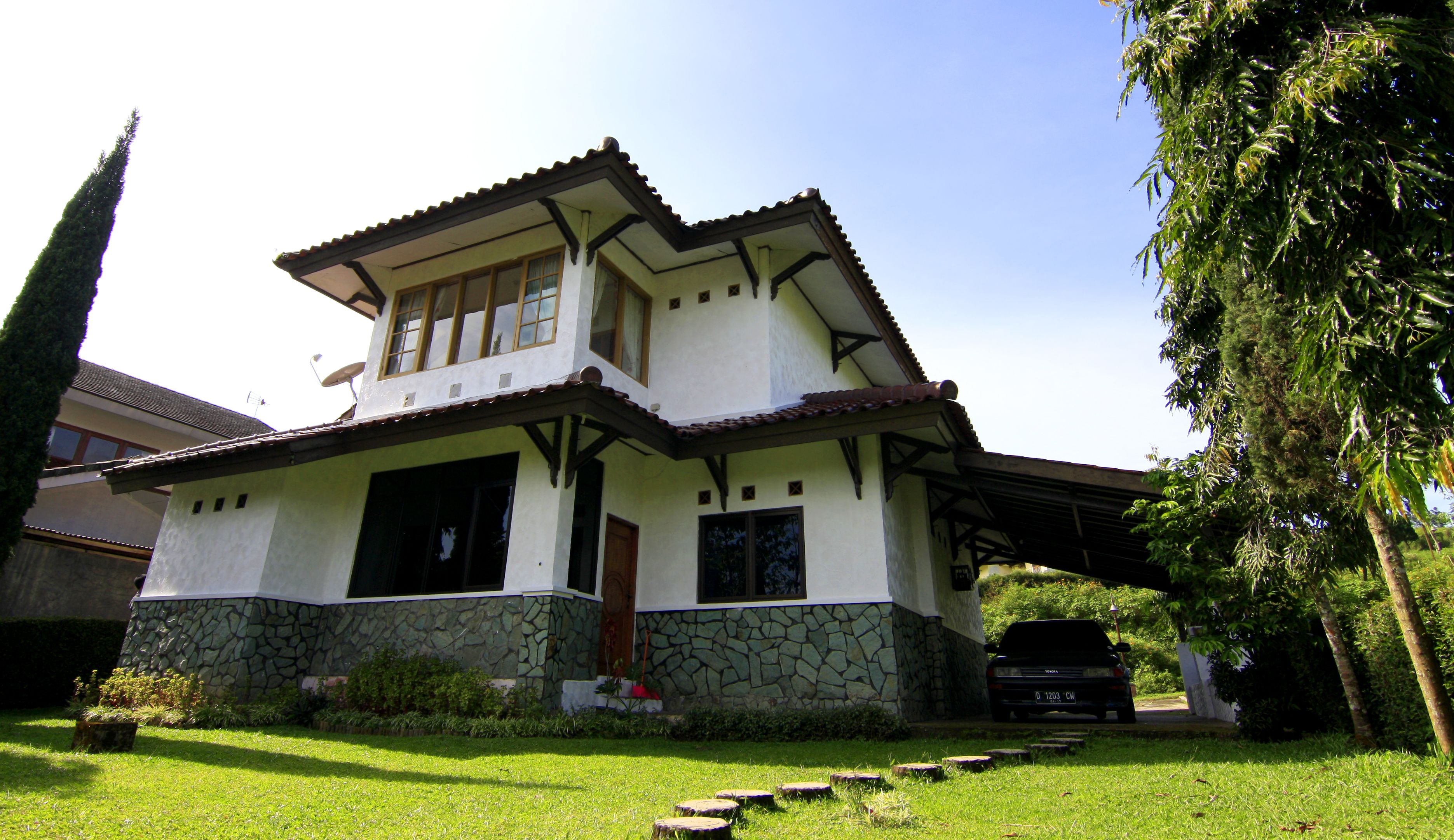 A two-story house with a stone foundation, a tiled roof, and a covered porch.
