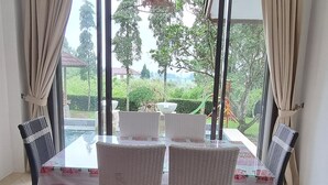 Ein Essbereich mit Tisch und Stühlen, großen Fenstern und Blick auf Grünflächen.