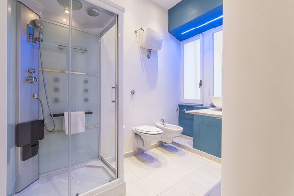 Un baño moderno con ducha de vidrio, inodoro y bidé.