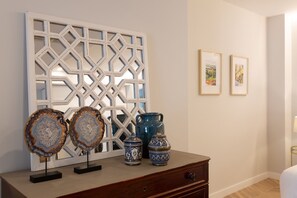 Una habitación con un panel decorativo de celosía blanca, dos posavasos de ágata y tres jarrones estampados en azul sobre un aparador de madera.