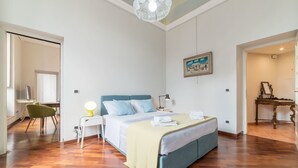 Un dormitorio con cama, mesita de noche, lámpara y un cuadro en la pared.