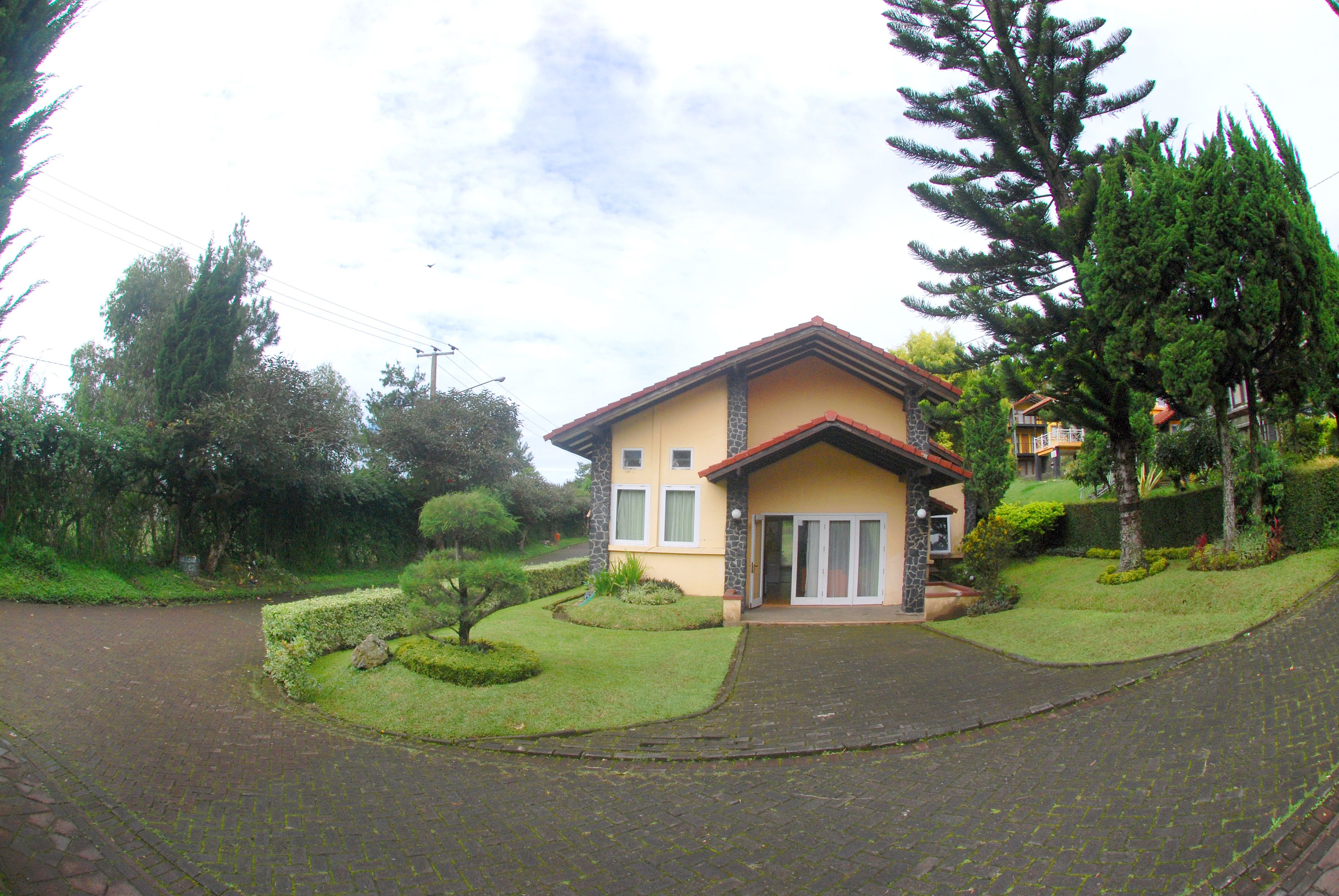 A two-story house with a stone facade, a tiled roof, and a paved driveway.