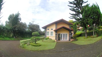 A two-story house with a stone facade, a tiled roof, and a paved driveway.