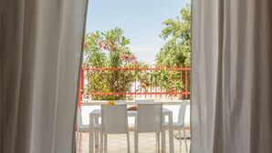 An outdoor seating area with white chairs and a table, a red fence, and greenery in the background. - Casa Gaia DX (Porto Cesareo)